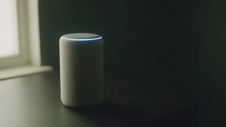 A smart speaker glowing blue on a dark table, the usual face of AI text-to-speech